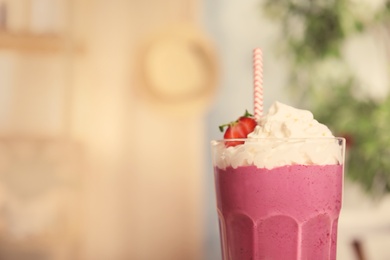 Photo of Tasty fresh milk shake with strawberry in glass indoors, closeup. Space for text