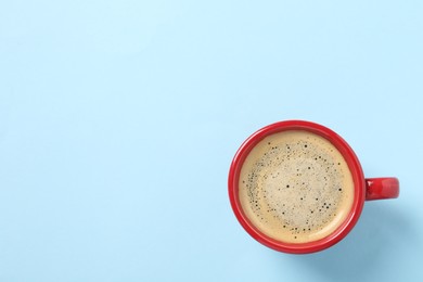Photo of Tasty coffee in cup on light blue background, top view. Space for text