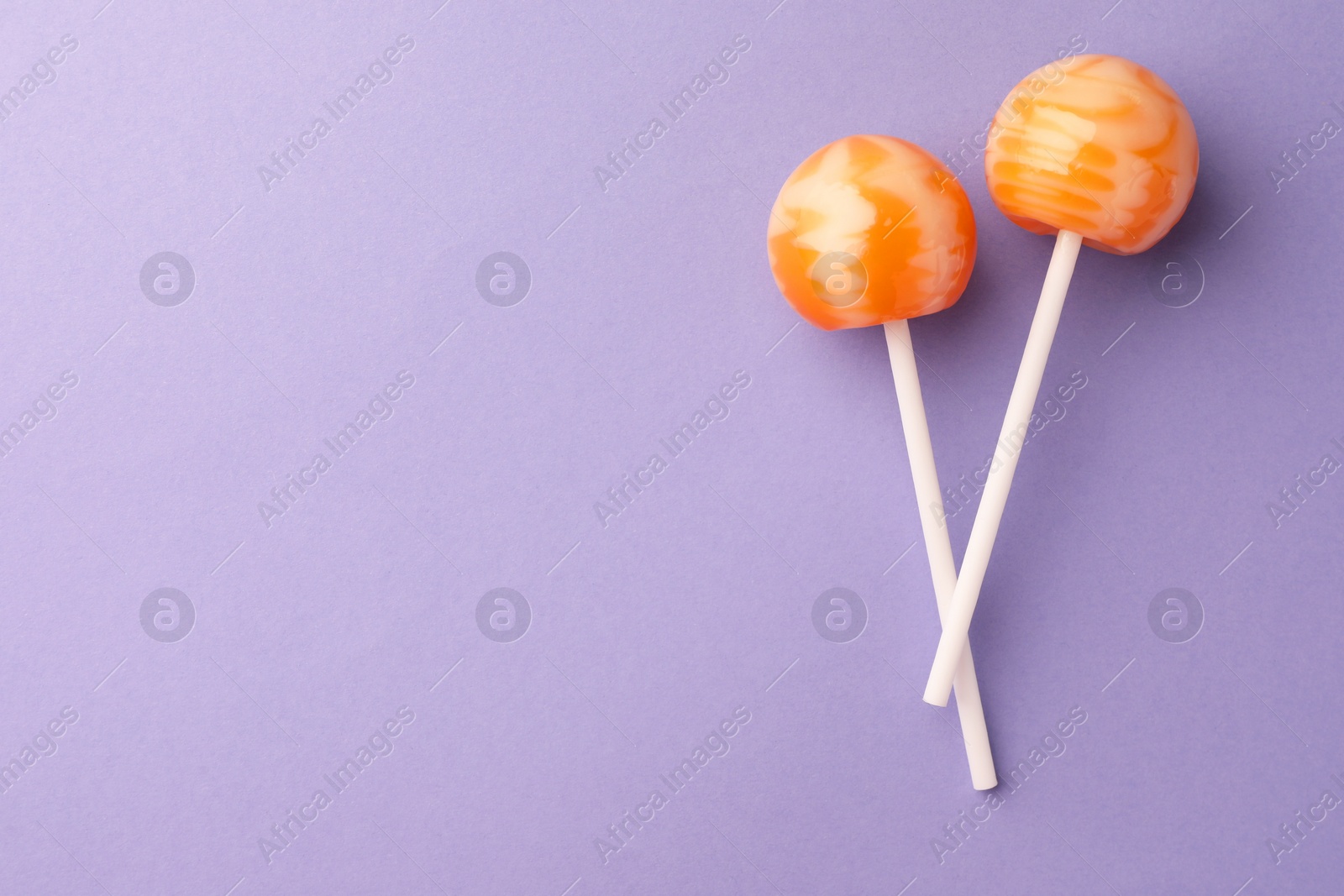 Photo of Tasty lollipops on violet background, flat lay. Space for text