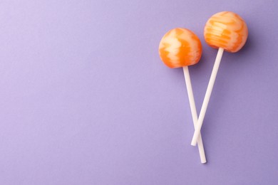 Tasty lollipops on violet background, flat lay. Space for text