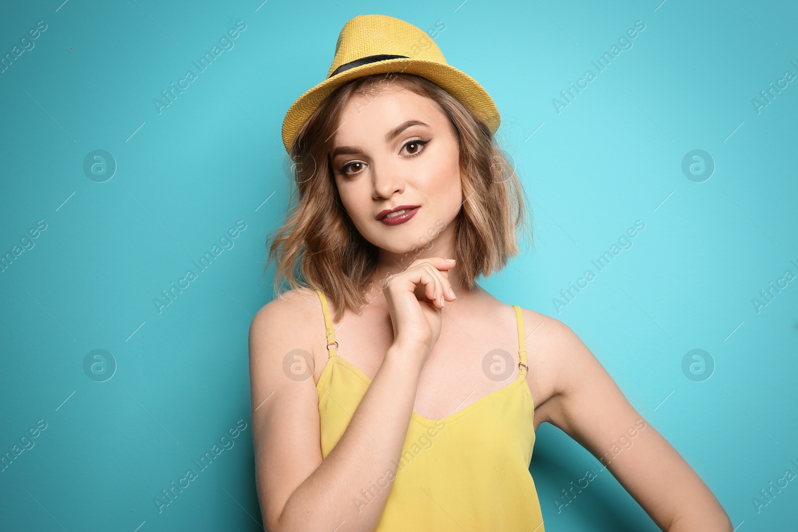 Photo of Beautiful young woman with stylish hat posing on color background
