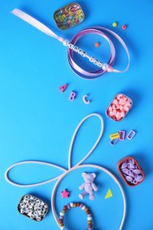 Handmade jewelry kit for kids. Colorful beads, ribbon and supplies on light blue background, flat lay