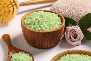 Photo of Bowls and scoop with sea salt, beautiful rose on white table, closeup