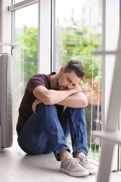 Photo of Lonely depressed man near window at home