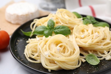 Delicious pasta with brie cheese and basil leaves on white table, closeup