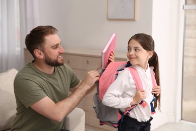 Father helping his little daughter to get ready for school indoors