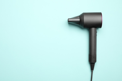 Hair dryer on light blue background, top view with space for text. Professional hairdresser tool