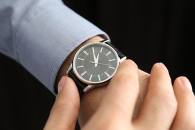 Man with luxury wrist watch on black background, closeup