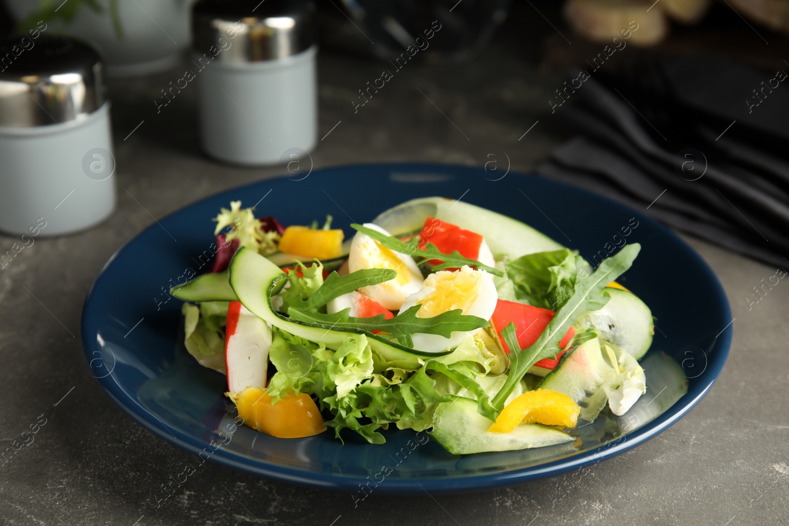 Photo of Delicious salad with crab sticks and lettuce on grey table, closeup