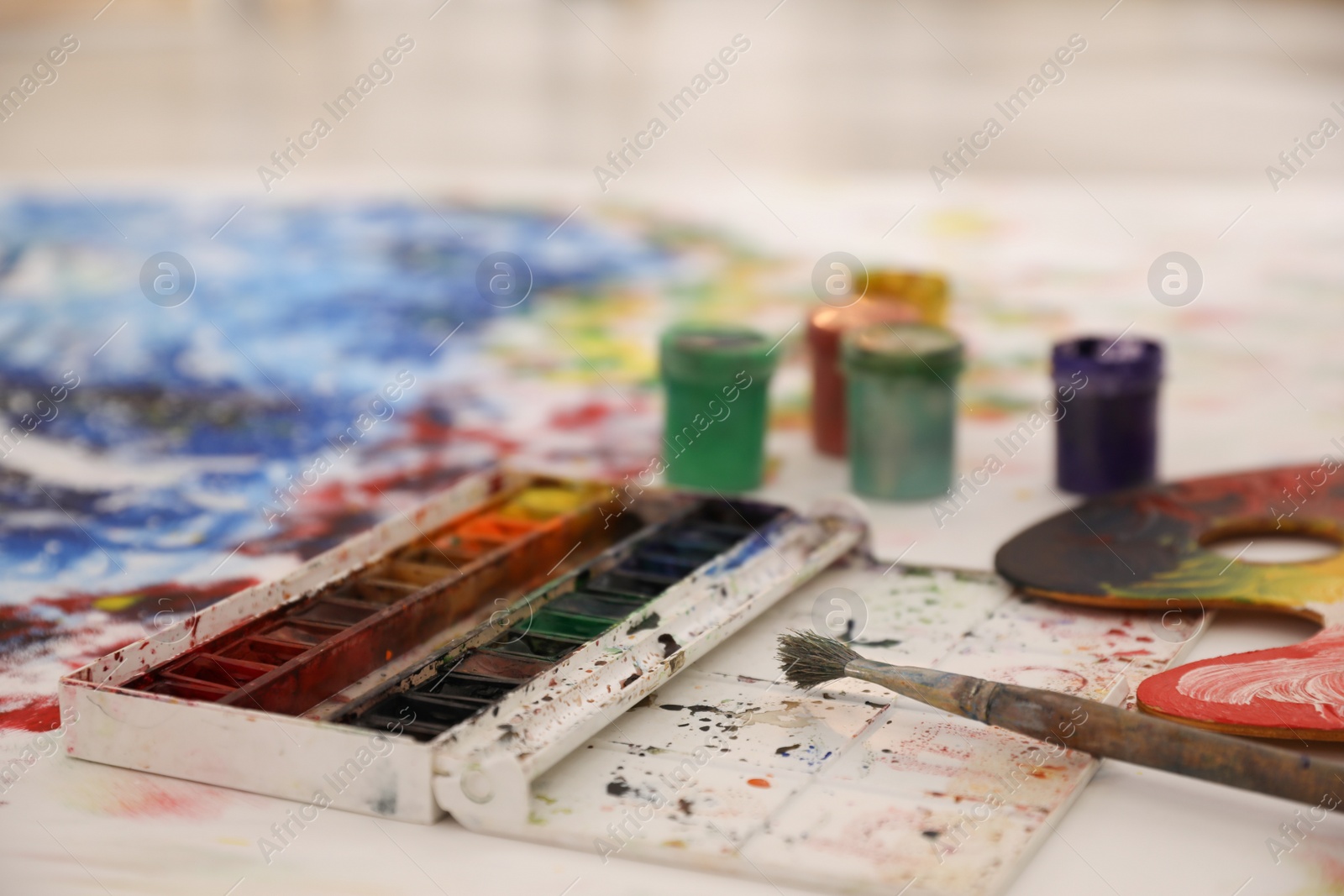 Photo of Box of paints and brush on abstract picture