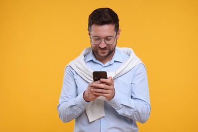 Photo of Happy man using smartphone on yellow background