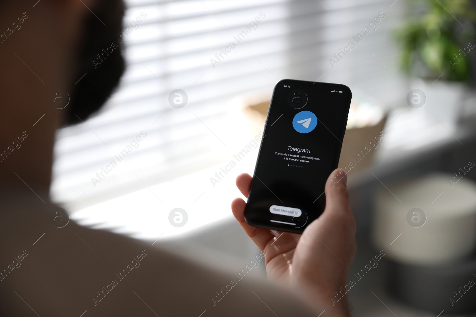 Photo of MYKOLAIV, UKRAINE - MARCH 16, 2020: Man holding iPhone 11 with Telegram app on screen indoors, closeup