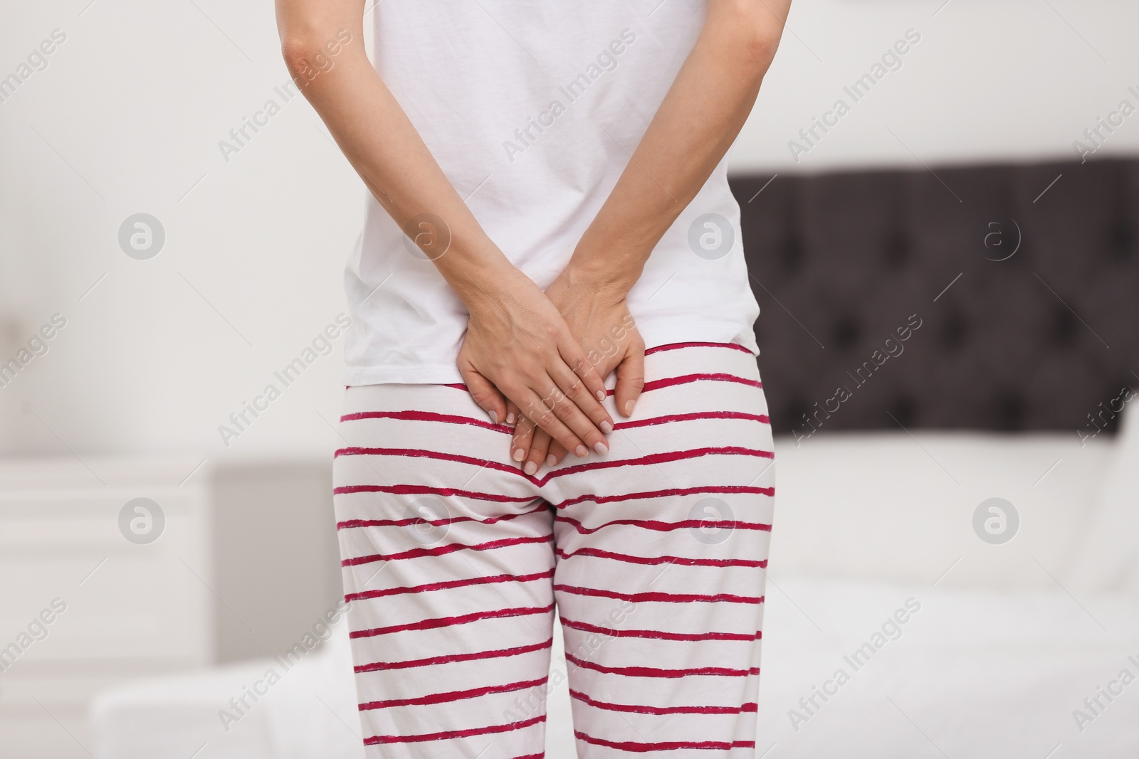 Photo of Young woman suffering from hemorrhoid in bedroom, closeup
