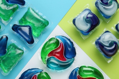 Different laundry capsules on color background, flat lay