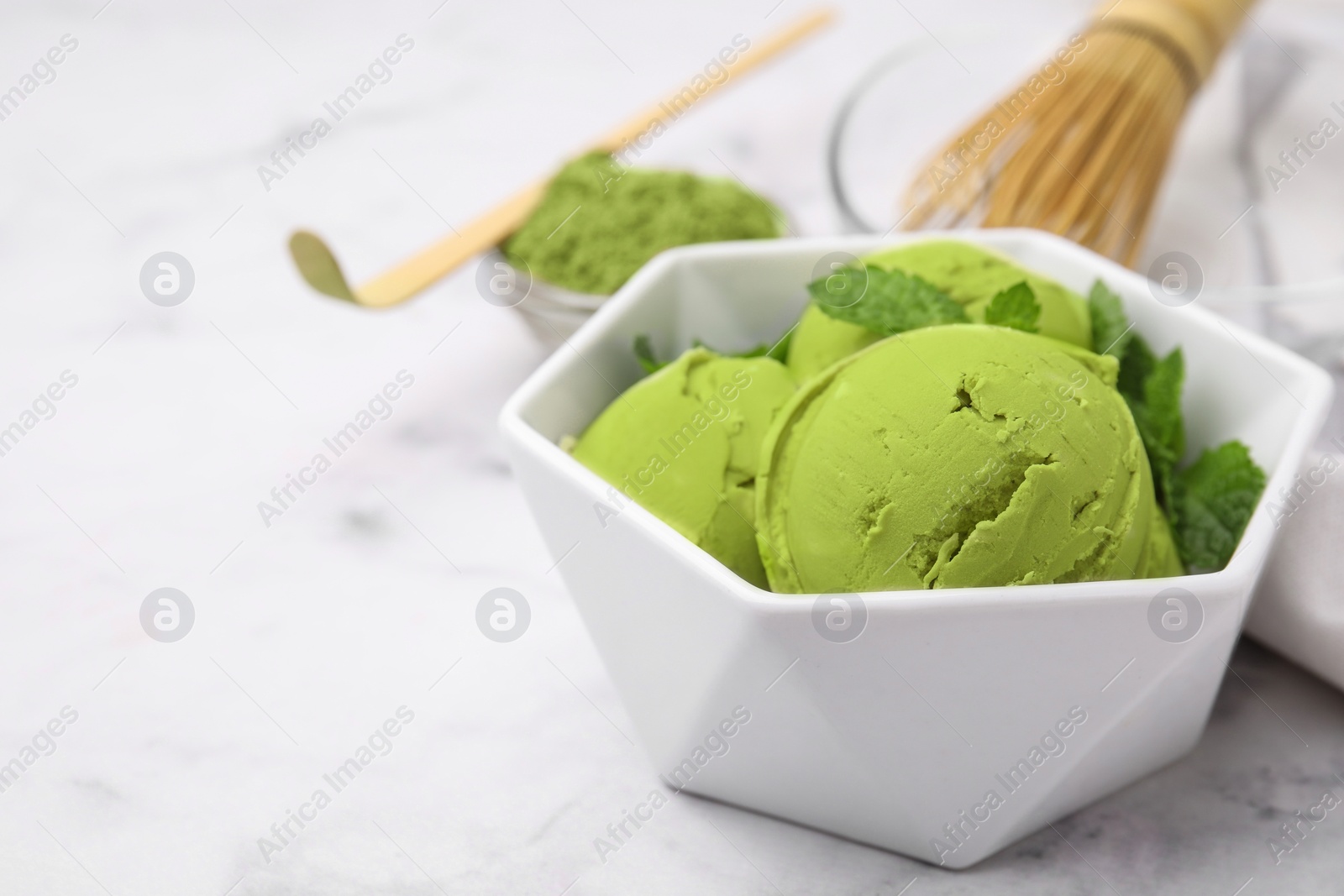 Photo of Tasty matcha ice cream in bowl on white table, closeup. Space for text