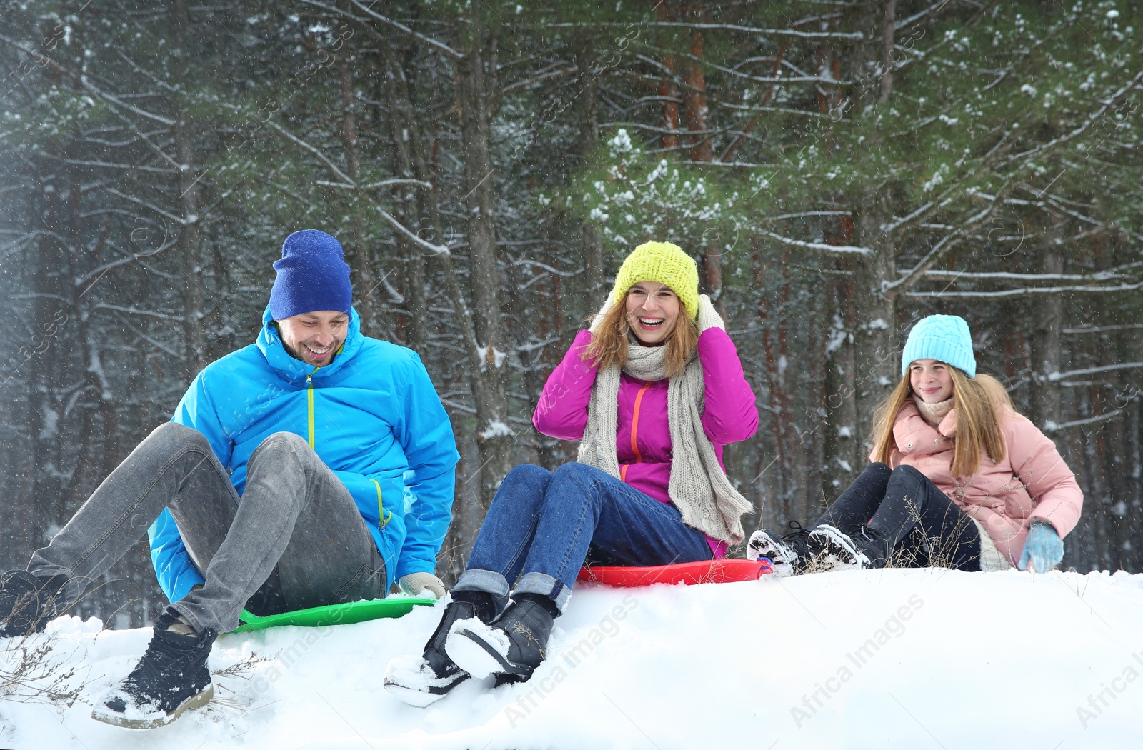 Photo of Happy family sledding in forest on snow day