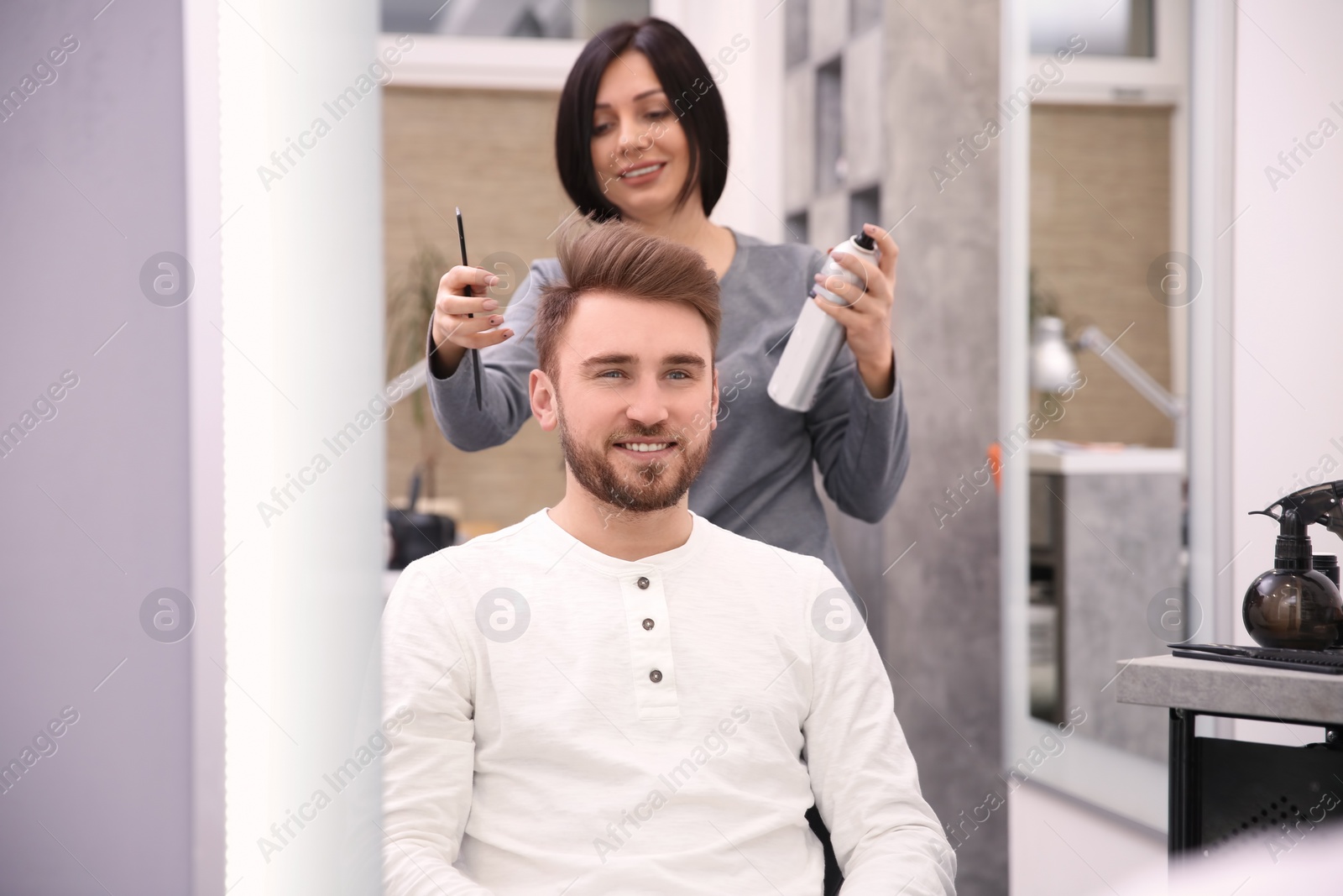 Photo of Professional female hairdresser working with client in salon