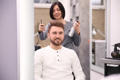 Photo of Professional female hairdresser working with client in salon