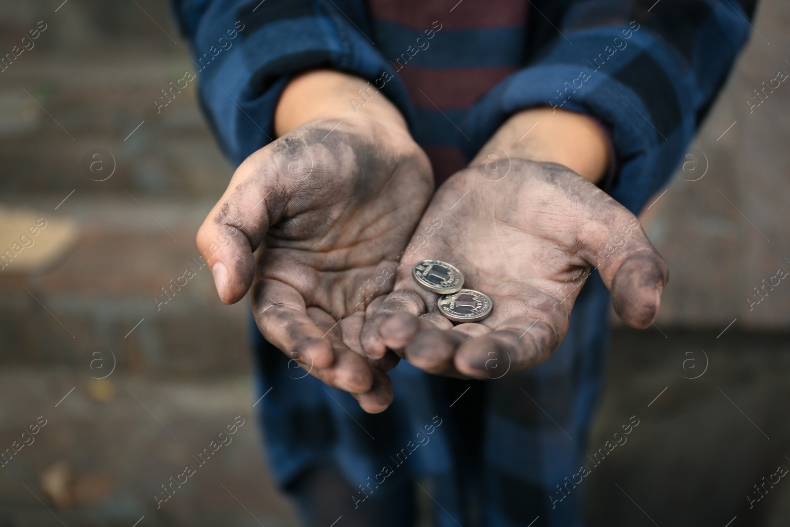 Photo of Poor homeless child with coins outdoors, closeup