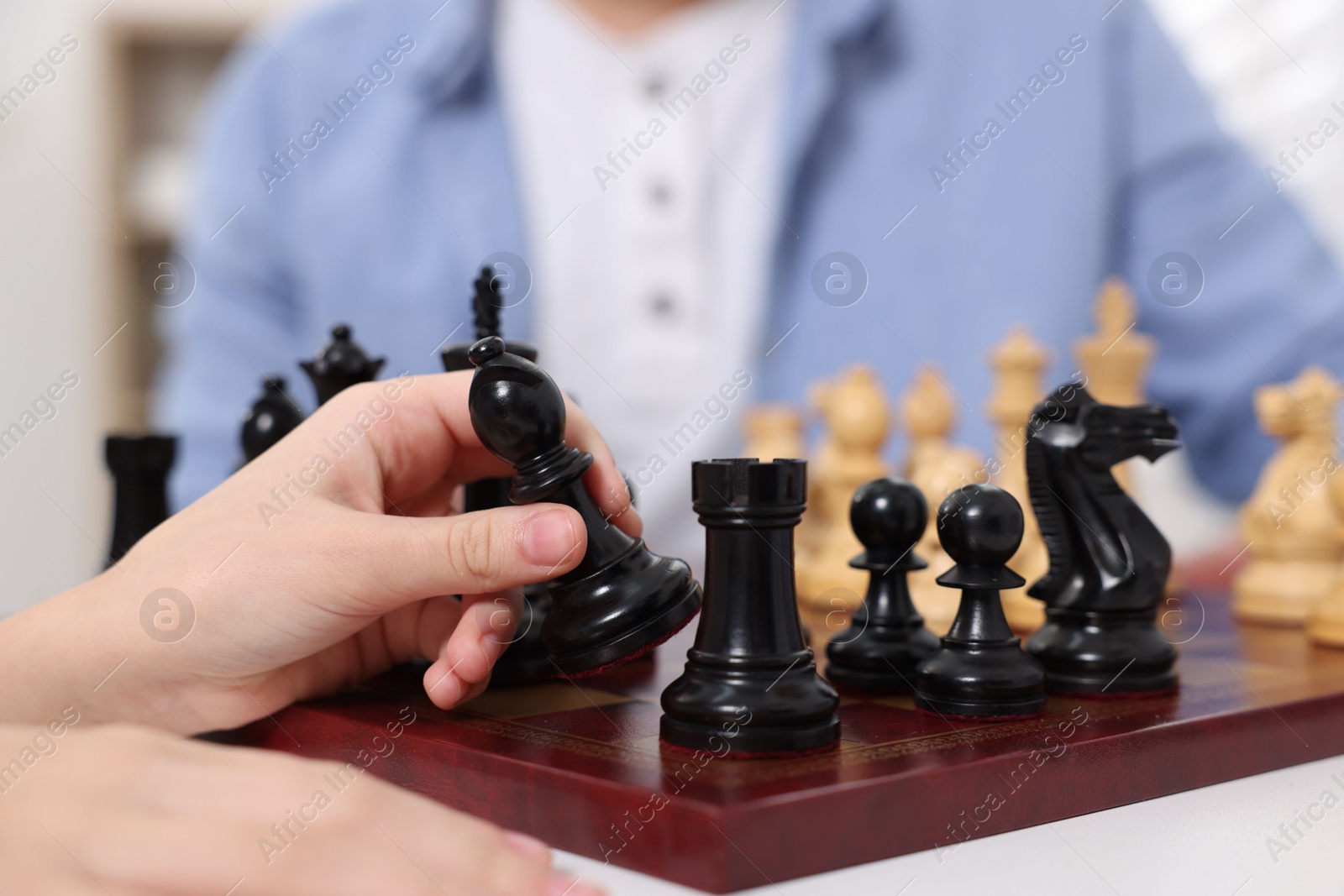 Photo of Little child playing chess with father indoors, closeup
