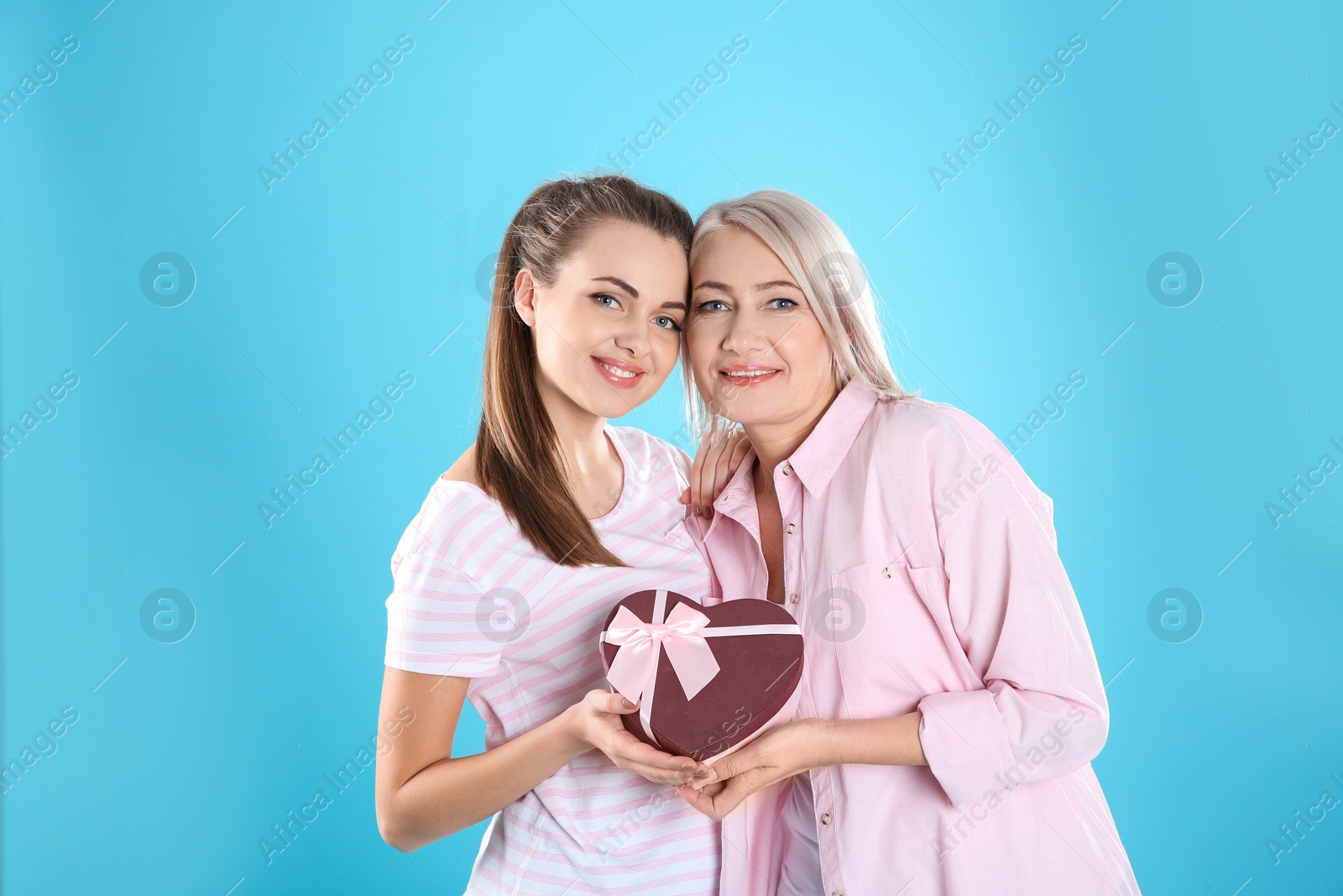 Photo of Young daughter congratulating her mature mother on color background. Happy Women's Day