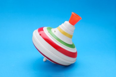 One bright spinning top on light blue background. Toy whirligig
