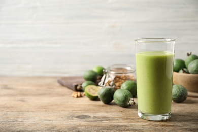 Photo of Fresh feijoa smoothie in glass on wooden table, space for text