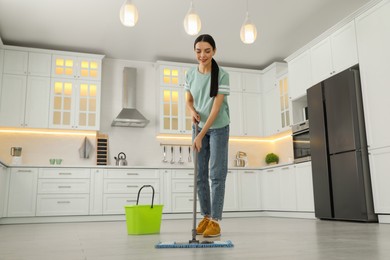 Woman cleaning floor with mop at home