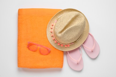 Photo of Beach towel, flip flops , sunglasses and hat on white background, top view