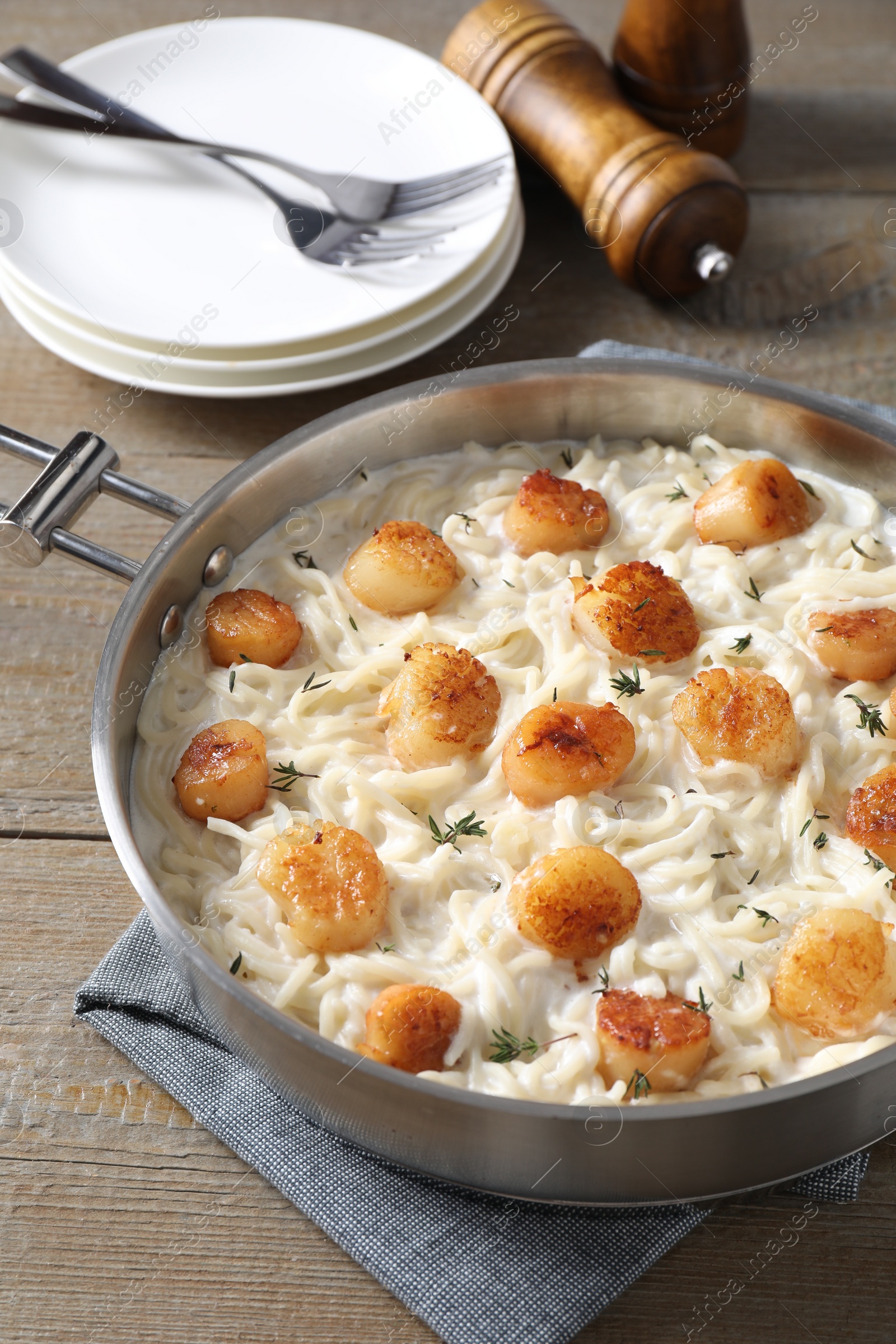 Photo of Delicious scallop pasta served on wooden table