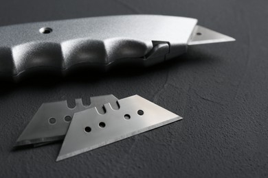 Photo of Utility knife and blades on black background, closeup