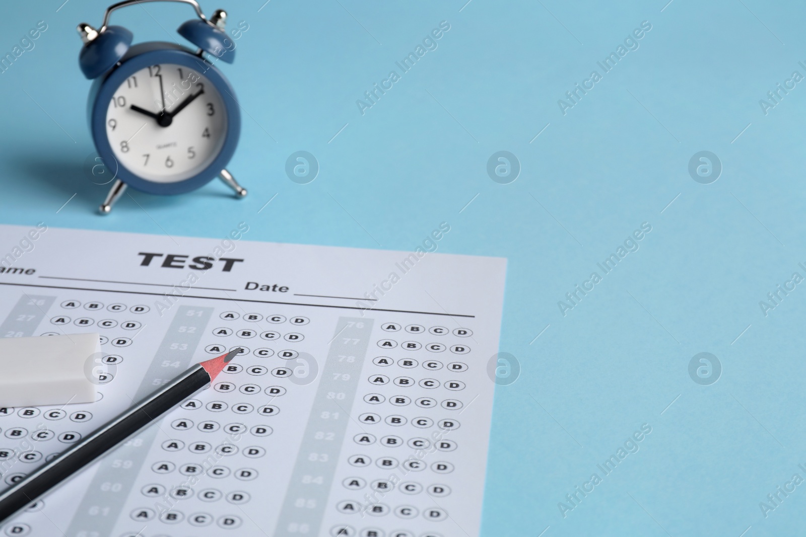 Photo of Answer sheet, pencil and alarm clock on light blue background, space for text. Student passing exam
