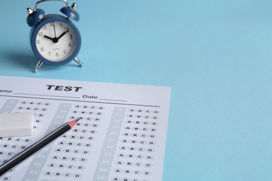 Answer sheet, pencil and alarm clock on light blue background, space for text. Student passing exam