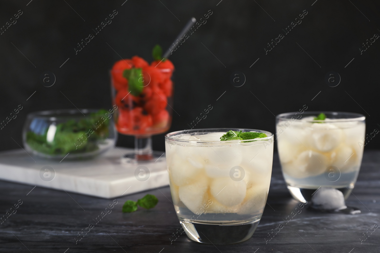 Photo of Glasses with tasty melon ball drinks on dark table