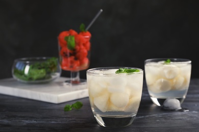 Glasses with tasty melon ball drinks on dark table