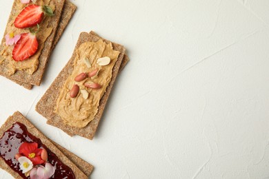 Fresh rye crispbreads with different toppings on white table, flat lay. Space for text