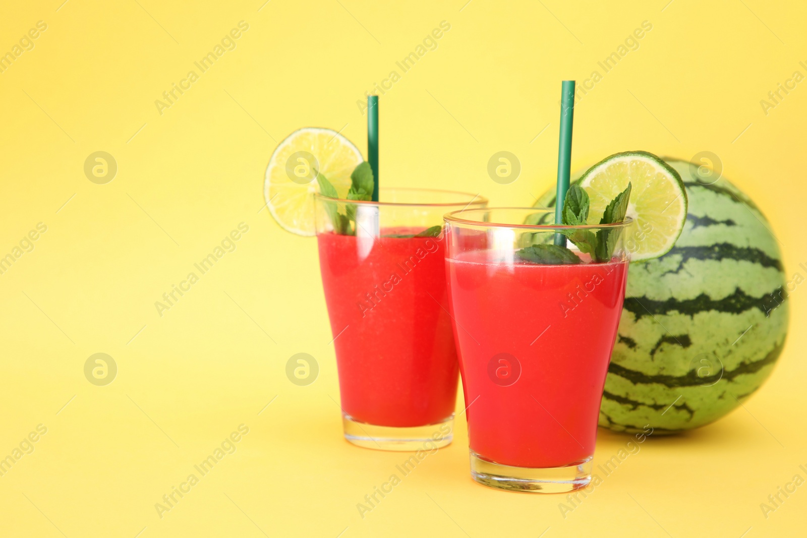 Photo of Delicious drink with mint, lime and fresh watermelon on yellow background, space for text