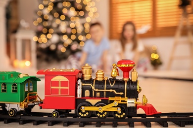 Photo of Children playing with colorful toy in room decorated for Christmas, focus on train