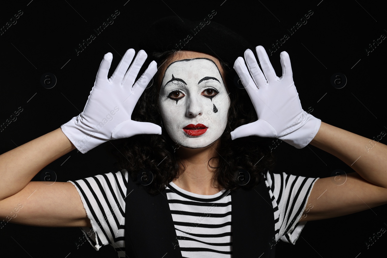 Photo of Young woman in mime costume posing on black background