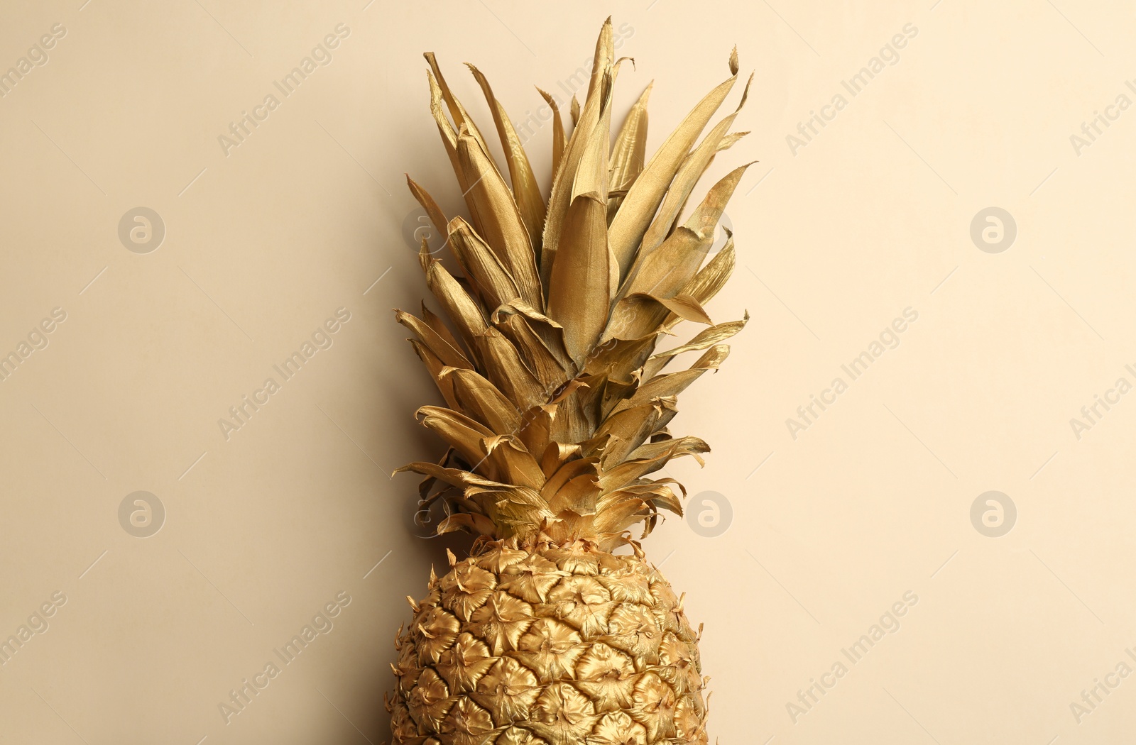 Photo of Golden pineapple on beige background, top view. Creative concept