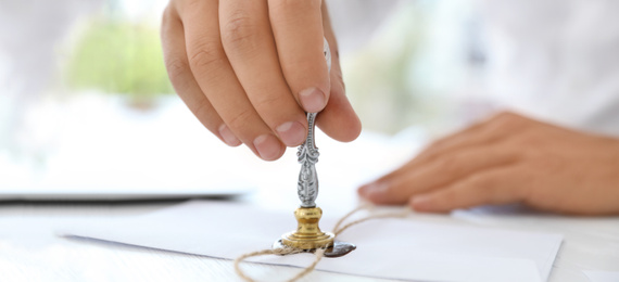 Image of Male notary stamping document at table, closeup. Banner design