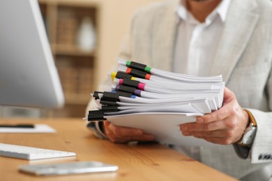 Businessman with documents at wooden table in office, closeup. Space for text