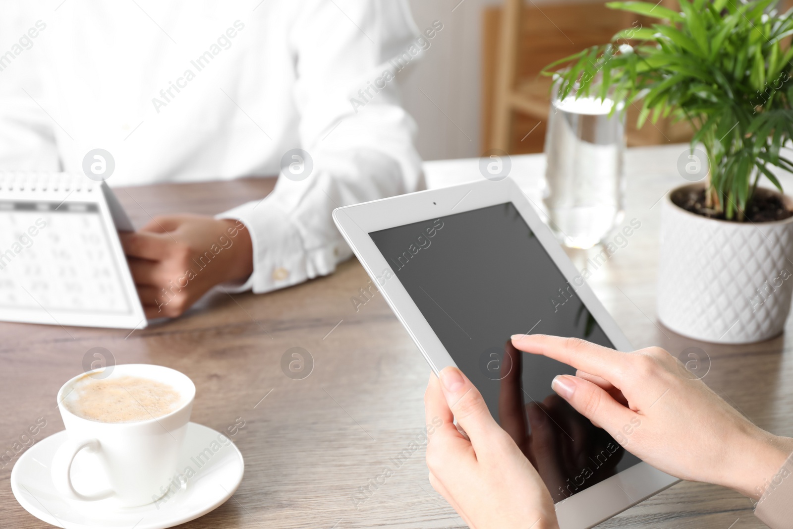 Photo of Woman using modern tablet at table indoors, closeup