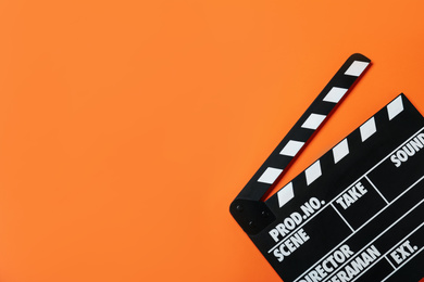 Photo of Clapper board on orange background, top view with space for text. Cinema production