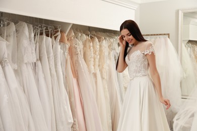 Woman trying on beautiful wedding dress in boutique