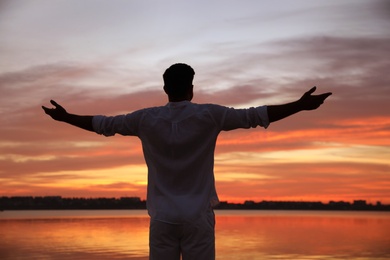 Photo of Man near river at sunset, back view. Nature healing power