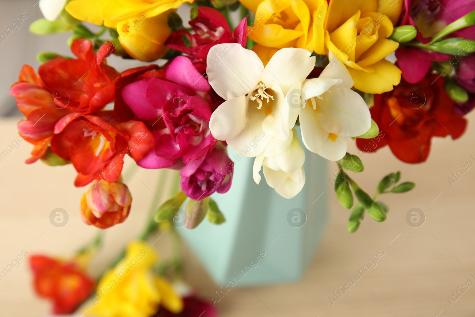 Photo of Beautiful spring freesia flowers on table, closeup