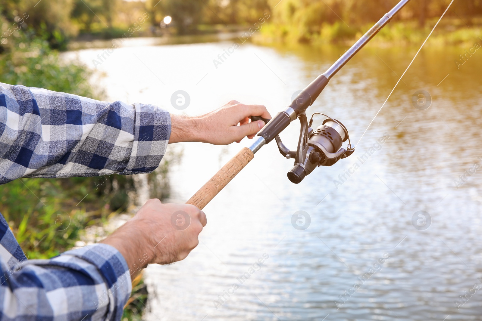 Photo of Man with rod fishing at riverside, focus on hands. Recreational activity