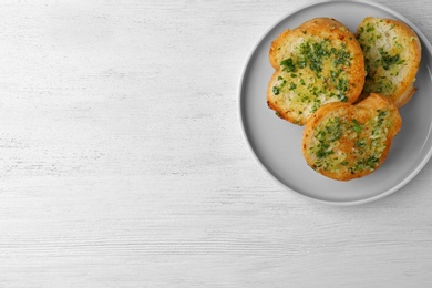 Photo of Slices of toasted bread with garlic and herbs on white wooden table, top view. Space for text