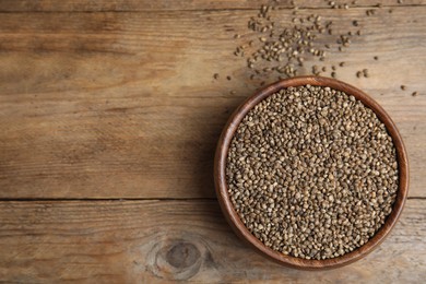 Photo of Bowl with organic hemp seeds on wooden table, flat lay. Space for text